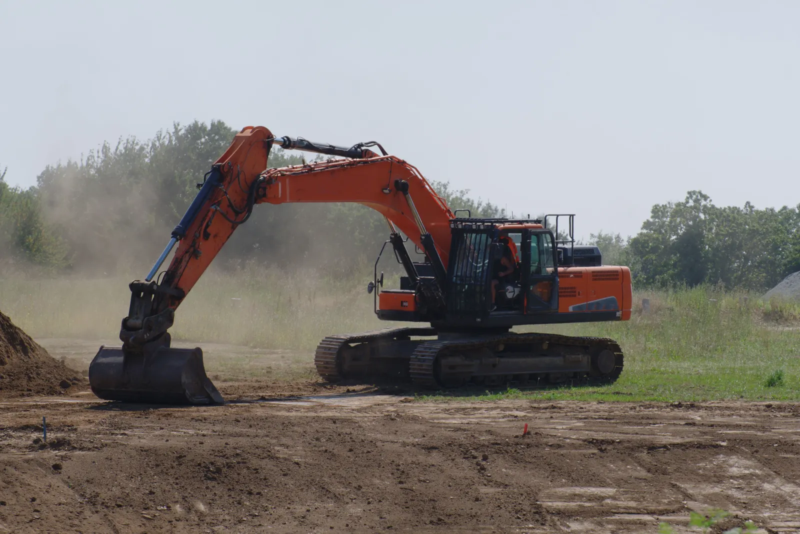 Pelle hydraulique nivelant un terrain en plein champ